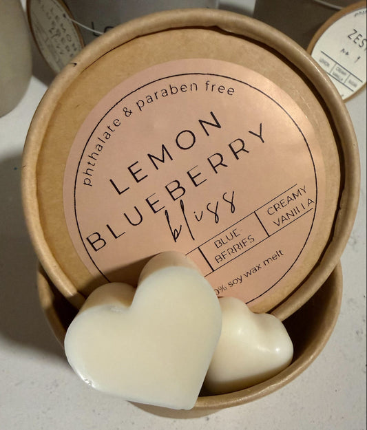 Heart-shaped lemon blueberry wax melts  in a cardboard container on a light surface.