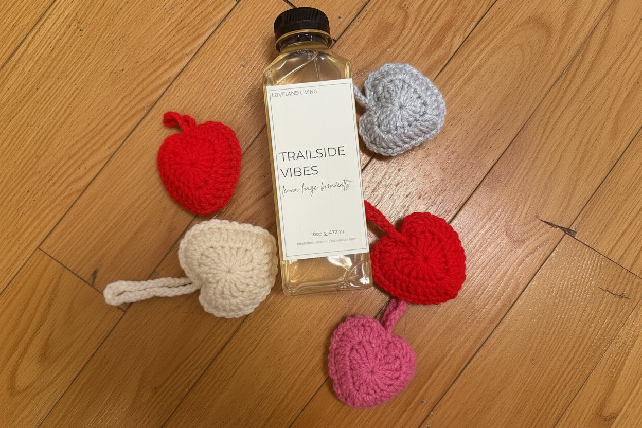 Bottle of 'Cupids arrow' product with crocheted heart-shaped coasters on a wooden surface